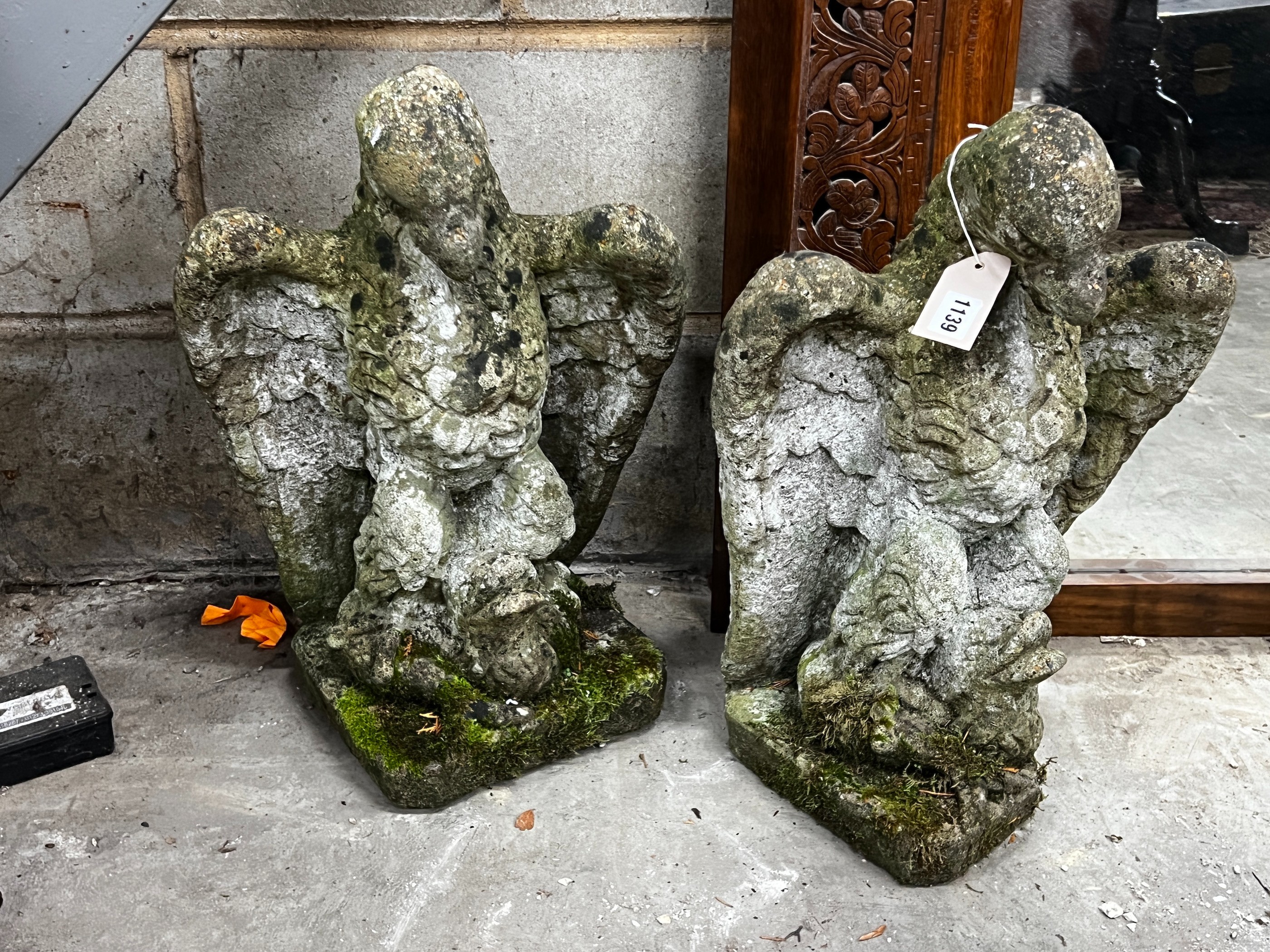 A pair of weathered reconstituted stone eagle and dolphin garden ornaments, height 52cm